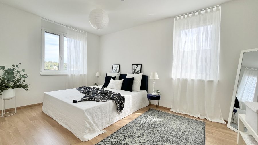 Helles, minimalistisches Schlafzimmer mit großem Bett und Holzfußboden.