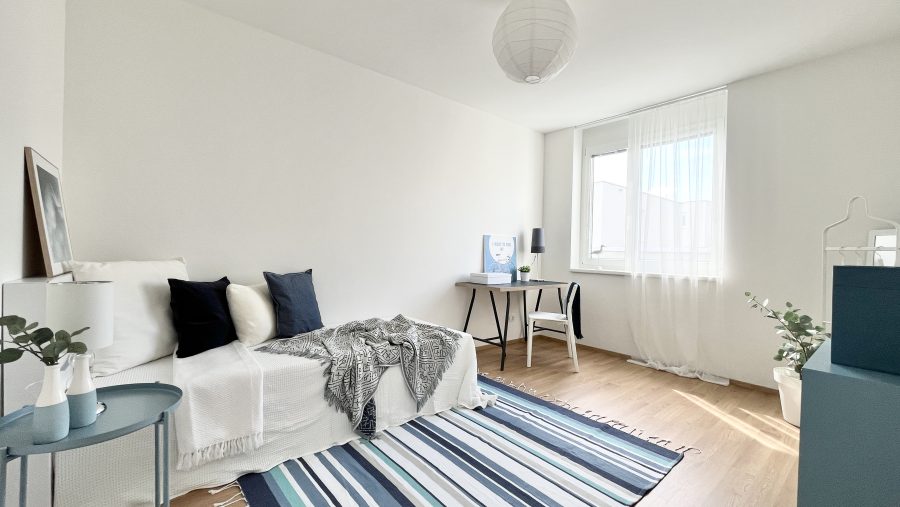 Helles, minimalistisches Wohnzimmer mit Sofa, Schreibtisch, Teppich und Fenstern. Skandinavisches Design.