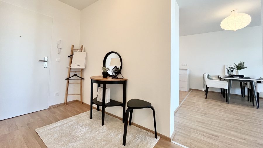 Moderner Eingangsbereich mit Tisch, Spiegel und Dekorationen, angrenzend an einen Essbereich.