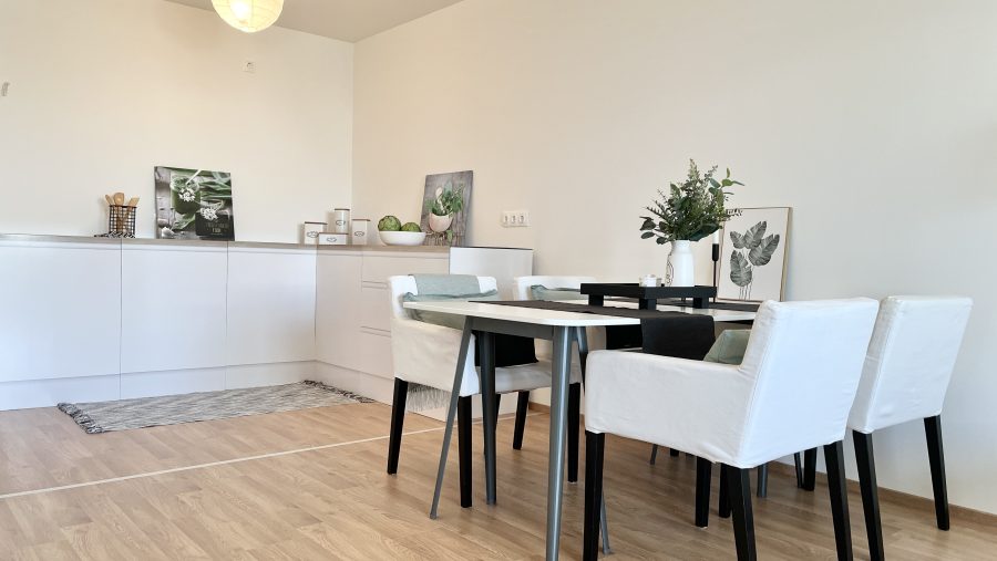 Moderner Essbereich mit Holzboden, weißem Tisch, vier Stühlen und minimalistischer Dekoration.