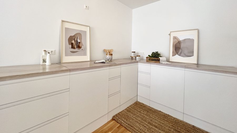 Moderne weiße Küche mit minimalistischer Dekoration und Holzarbeitsplatte.