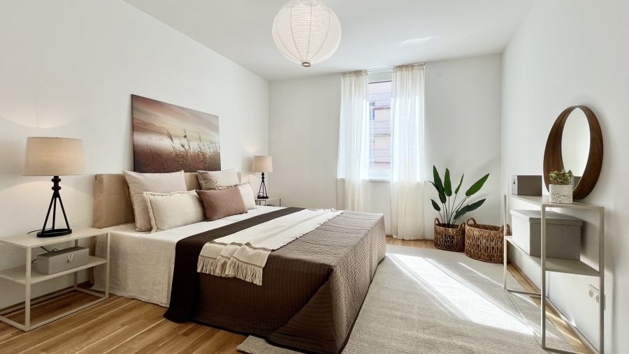 Modernes Schlafzimmer mit gemütlichem Bett, Lampen und dekorativer Pflanze.