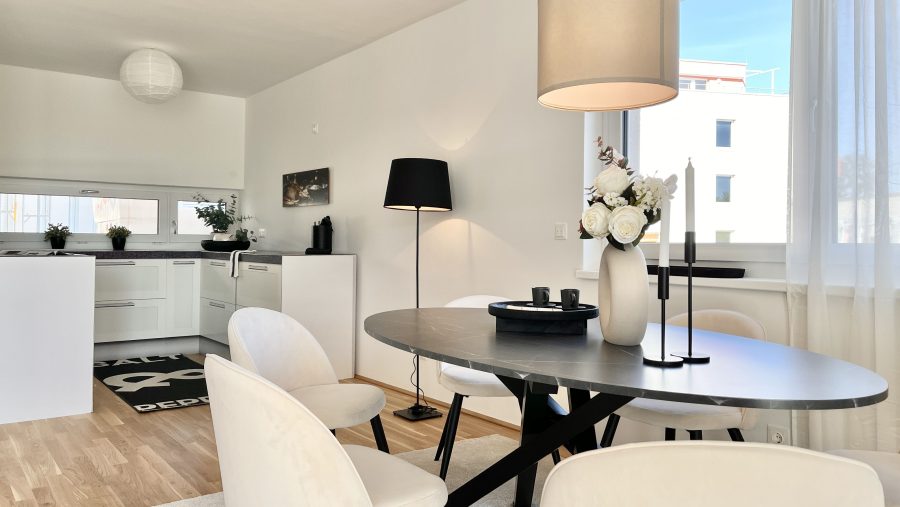 Moderner Essbereich mit elegantem Tisch, weißen Stühlen und geschmackvoller Dekoration in heller Wohnung.