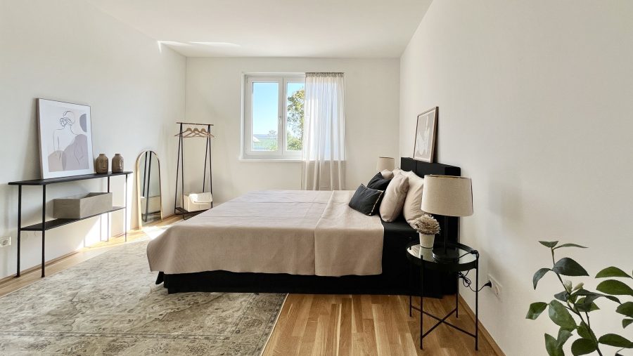 Minimalistisch eingerichtetes Schlafzimmer mit Bett, Pflanzen und Fenster in modernem Design.