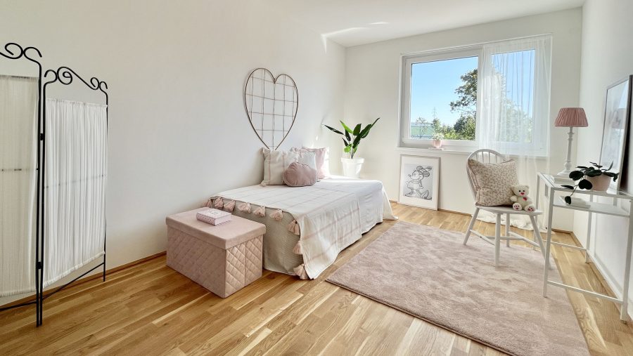 Helles, stilvolles Kinderzimmer mit Bett, Pflanzen und Holzboden, dekoriert in sanften Rosa- und Weißtönen.