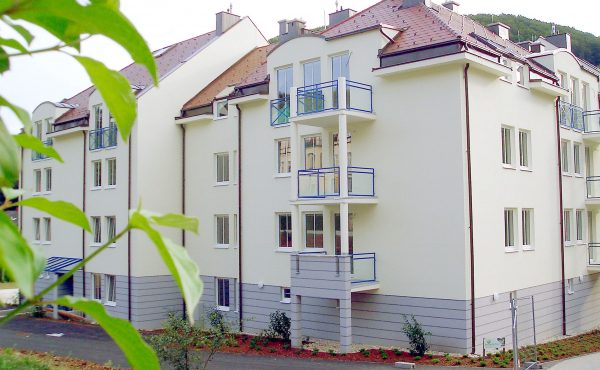 Moderne Wohnanlage mit mehreren Balkonen und grüner Umgebung.