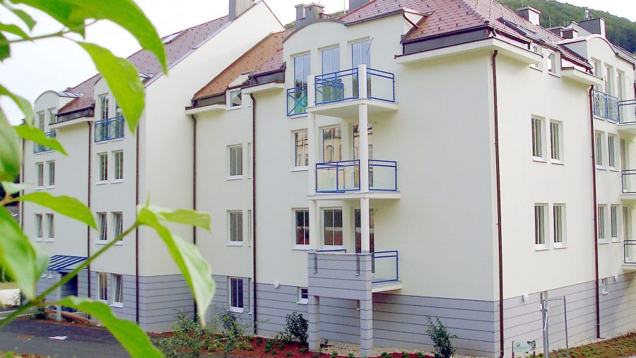 Moderne Wohnanlage mit mehreren Balkonen und grüner Umgebung.