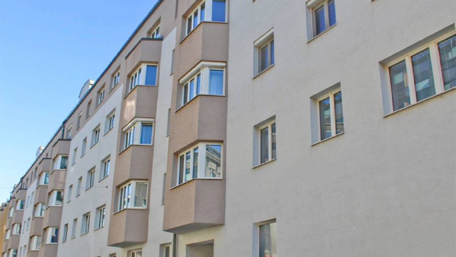 Wohngebäude mit modernen Fenstern und blauem Himmel im Hintergrund.