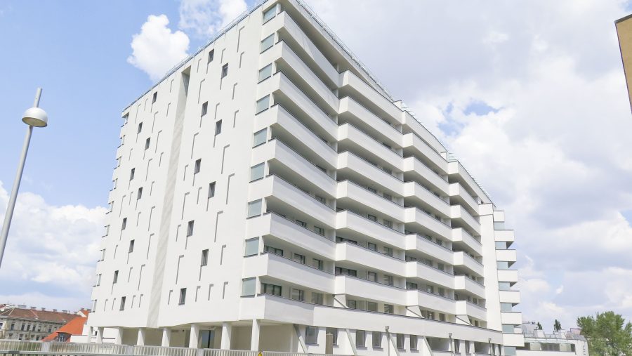 Modernes Wohngebäude vor bewölktem Himmel, aufgenommen von der Straßenseite.