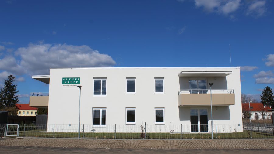 Modernes zweistöckiges Bürogebäude bei sonnigem Wetter mit klarem Himmel im Hintergrund.