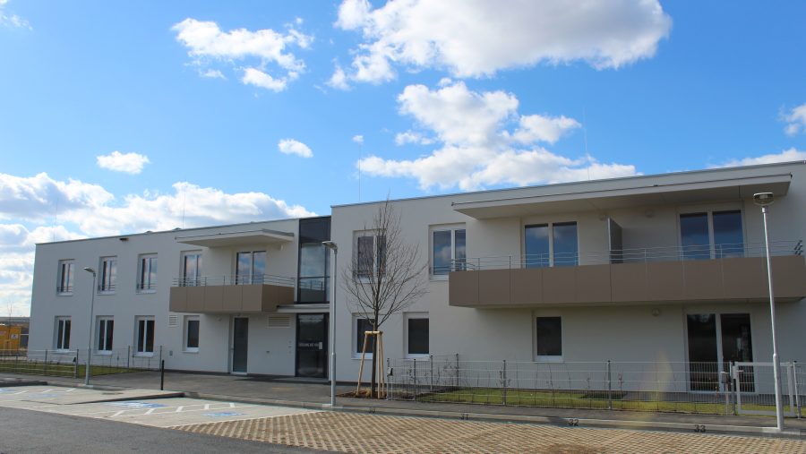 Modernes Gebäude bei Tageslicht mit blauem Himmel und Wolken im Hintergrund.