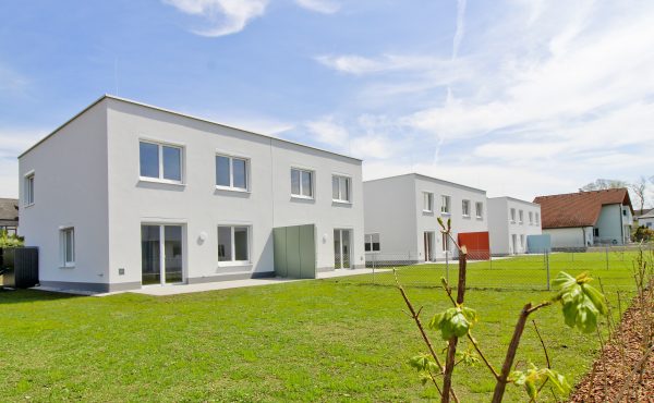 Moderne Wohngebäude mit Garten bei Sonnenschein, moderner Neubau architektonisch ansprechend und energieeffizient.