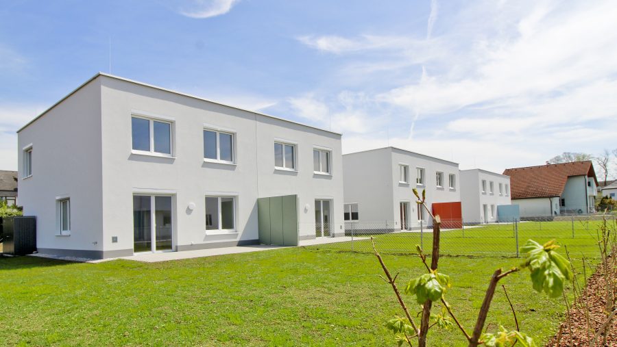 Moderne Wohngebäude mit Garten bei Sonnenschein, moderner Neubau architektonisch ansprechend und energieeffizient.