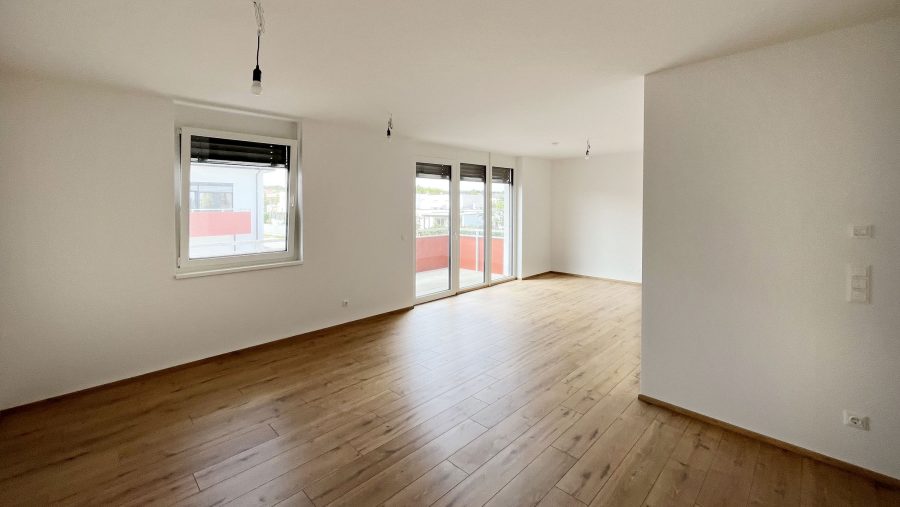 Helles, modernes Wohnzimmer mit Holzboden und großen Fenstern für viel Tageslicht.
