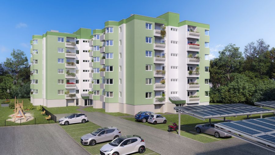 Mehrfamilienhaus mit grüner Fassade, Solardach-Carports und grünem Parkplatz bei sonnigem Wetter.