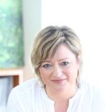 Portrait einer professionellen Immobilienberaterin in hellem, modernem Büro.