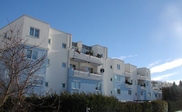 Mehrfamilienhaus im Winter mit blauem Himmel im Hintergrund.