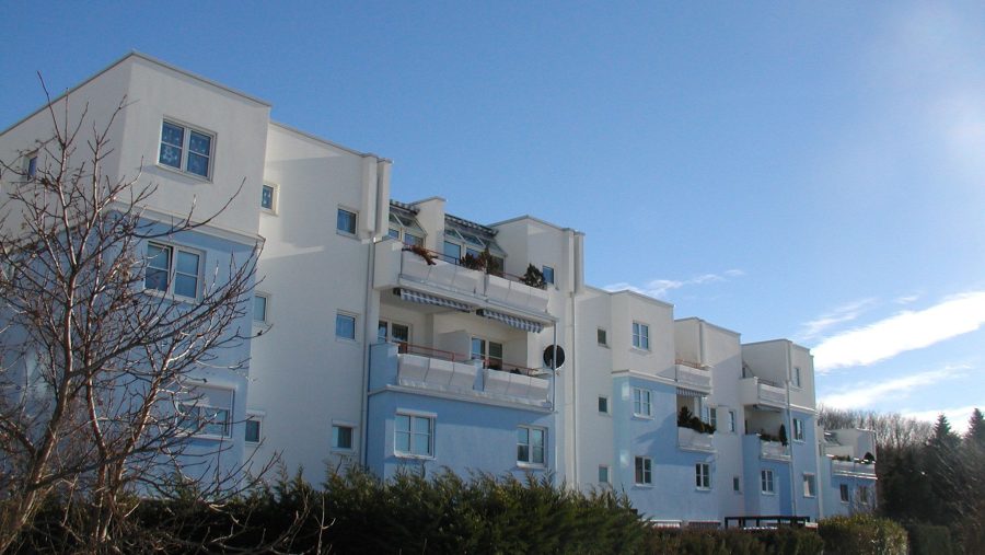 Mehrfamilienhaus im Winter mit blauem Himmel im Hintergrund.
