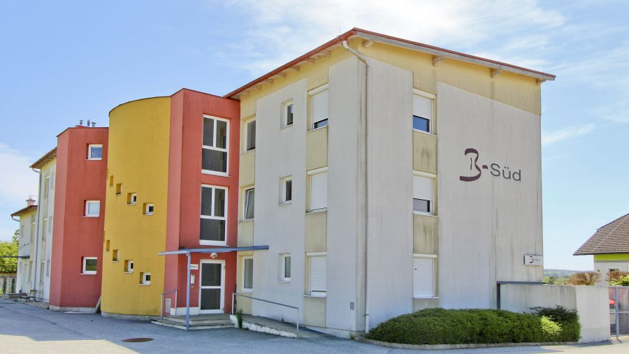 Mehrstöckiges Wohngebäude mit bunter Fassade und blauen Himmel im Hintergrund.