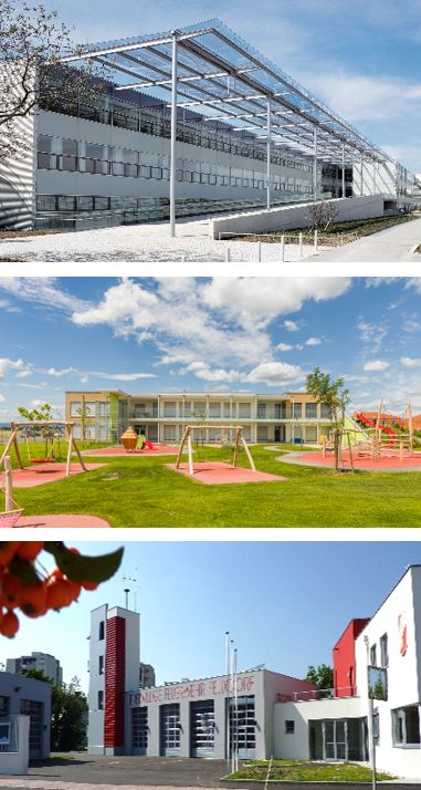 "Dr. Bruno Kreisky Schule" - Kindergarten Theresienfeld - Feuerwehr Felixdorf Drei moderne Gebäude, darunter ein Spielplatz, Feuerwehrstation und Bürogebäude bei blauem Himmel.