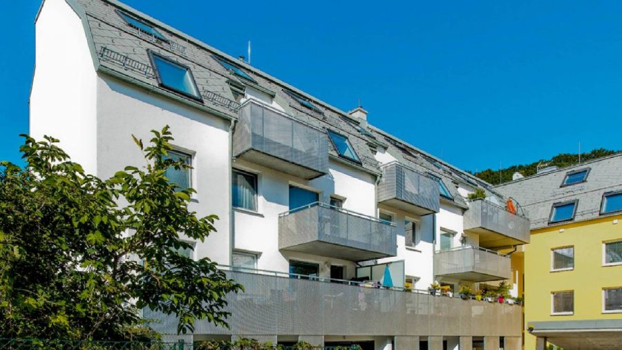 Mehrfamilienhaus mit Balkonen an einem sonnigen Tag, moderne Architektur.