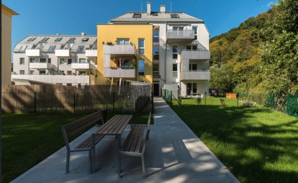 Moderne Wohngebäude mit Garten und Sitzbereich an einem sonnigen Tag.