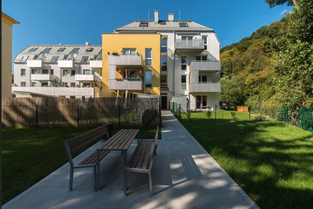 Moderne Wohngebäude mit Garten und Sitzbereich an einem sonnigen Tag.