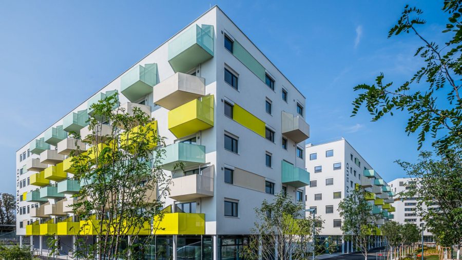 Moderne Wohngebäude mit bunten Balkonen vor blauem Himmel.