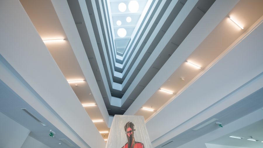 Modernes Atrium mit mehrstöckigem Innenraum und abstrakter Kunst im Vordergrund.