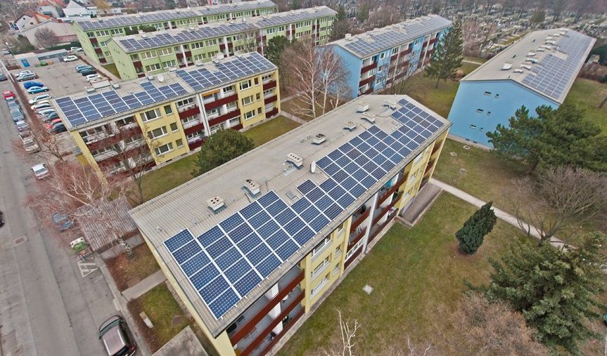 Mehrfamilienhäuser mit Solarpanels auf den Dächern in einer Wohngegend.