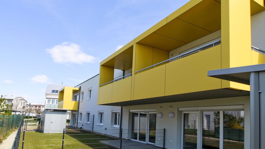 Moderne zweistöckige Gebäude mit gelben Balkonen unter blauem Himmel.