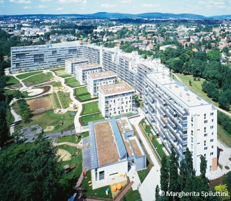 Referenz "Osramgründe" Moderne Wohnanlage mit Grünflächen, umgeben von Parklandschaft und Stadtpanorama im Hintergrund.