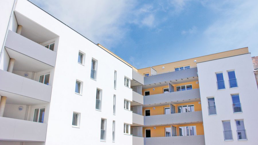 Moderne Wohngebäude mit Balkonen und Fenstern unter blauem Himmel.