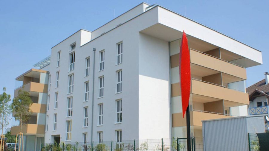 Modernes Wohngebäude mit Balkonen und blauer Himmel im Hintergrund.