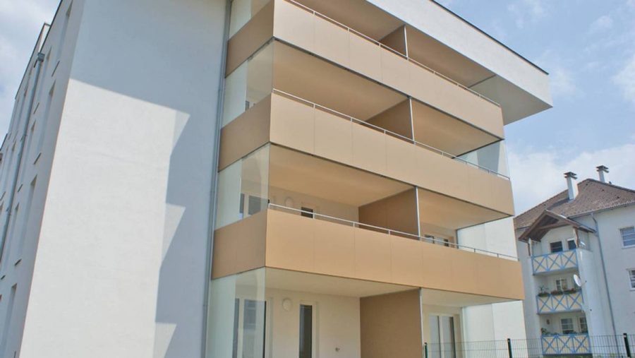 Modernes Mehrfamilienhaus mit Balkonen an der Außenseite bei klarem Himmel.