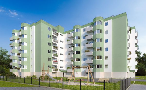 Mehrstöckiges Wohngebäude mit grün-weißer Fassade und Spielplatz im Vordergrund.