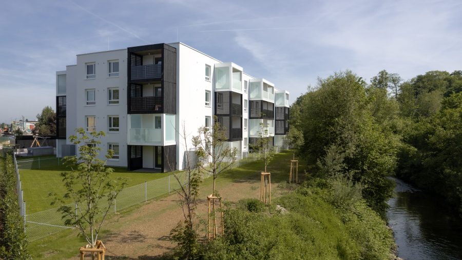 Moderne Wohnanlage neben Fluss mit gepflegtem Garten und Neubauten im Freien.
