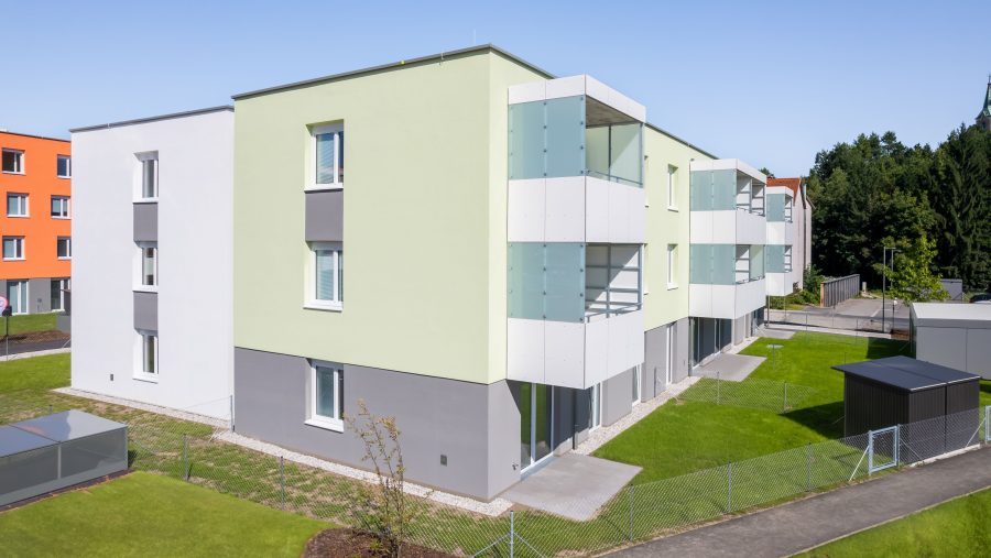 Moderne mehrstöckige Wohngebäude mit bunten Fassaden und Grünflächen im Außenbereich.