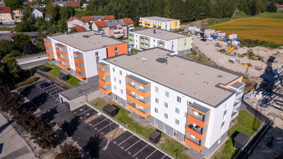 Mehrfamilienhäuser mit Parkplätzen in einer grünen Vorstadtsiedlung.