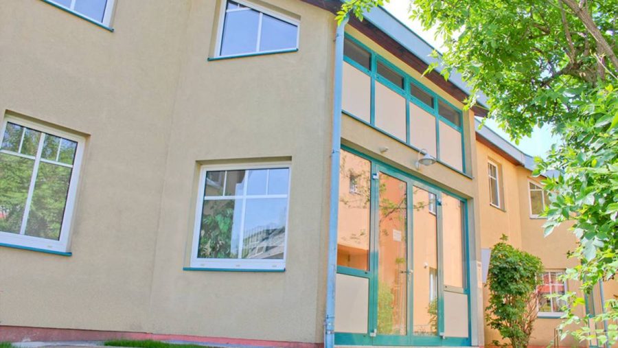 Modernes Wohngebäude mit großen Fenstern und Garten im Vordergrund.