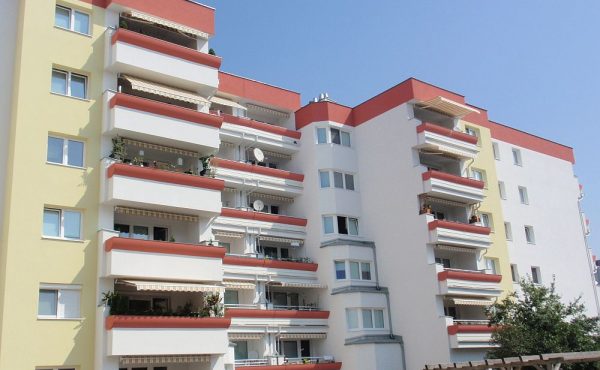 Mehrstöckiges Wohngebäude mit Balkonen an einem sonnigen Tag.