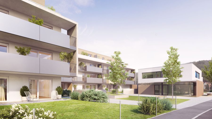 Moderne Wohngebäude mit Balkonen und Garten, blauer Himmel im Hintergrund.