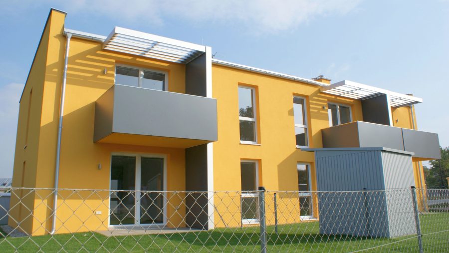 Attraktives modernes Haus mit gelber Fassade und Balkon in ruhiger Lage. Ideal für Familien, die eine Immobilie suchen.