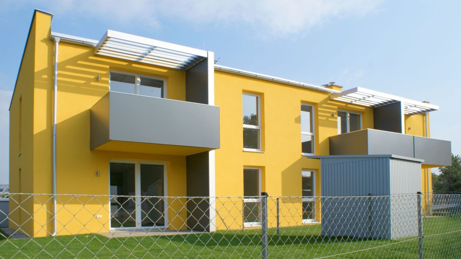 Modernes, gelbes Mehrfamilienhaus mit Balkonen und Garten zu verkaufen. Ideal für Familien in Wien.