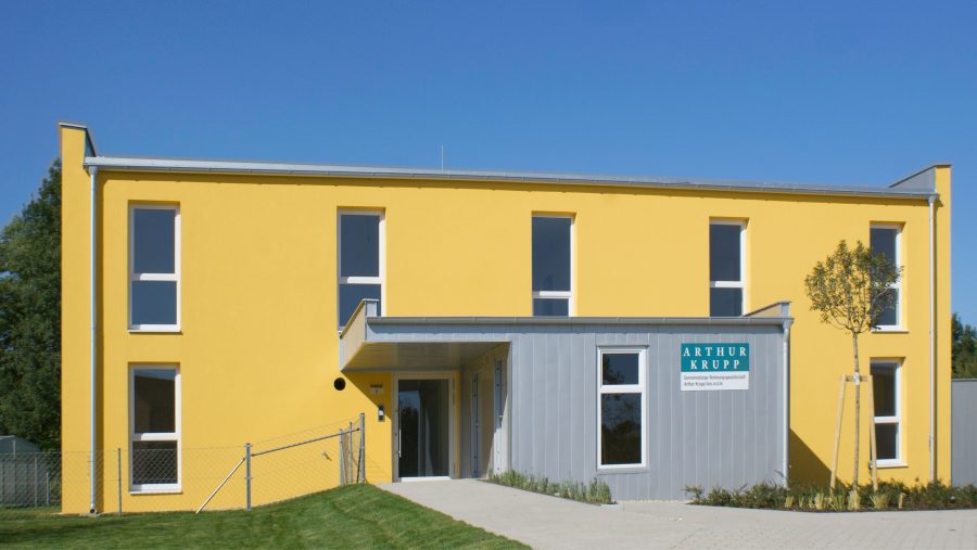 Moderne gelbe Gewerbeimmobilie mit großem Eingangsbereich.