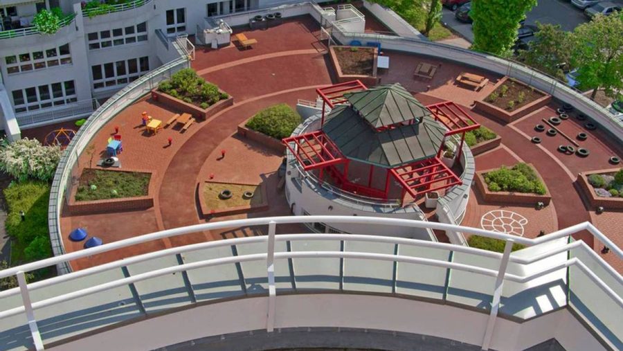 Dachterrasse eines modernen Wohnkomplexes mit Spielbereich und Sitzmöglichkeiten in städtischer Umgebung.