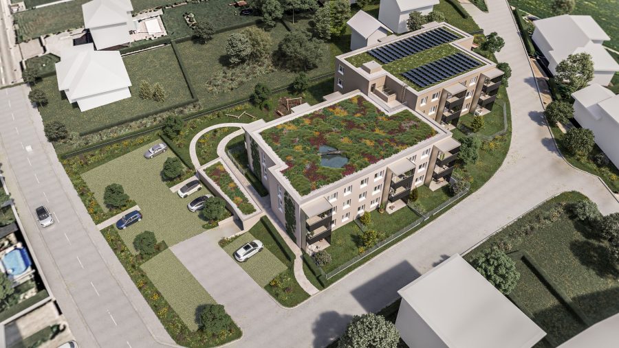 Luftaufnahme eines grünen Gebäudes mit Solaranlagen und bepflanztem Dach in einer Wohngegend.