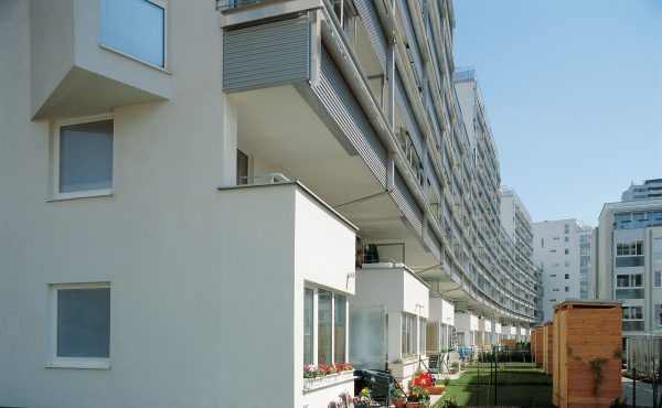 Moderne Wohngebäude mit Balkonen und Grünflächen an einem sonnigen Tag.
