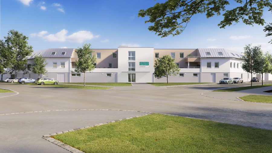 Modernes Gebäude mit Autos im Vordergrund, umgeben von Bäumen und blauem Himmel.